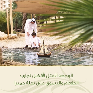 A father and son playing with a toy sailboat by the water in an outdoor setting